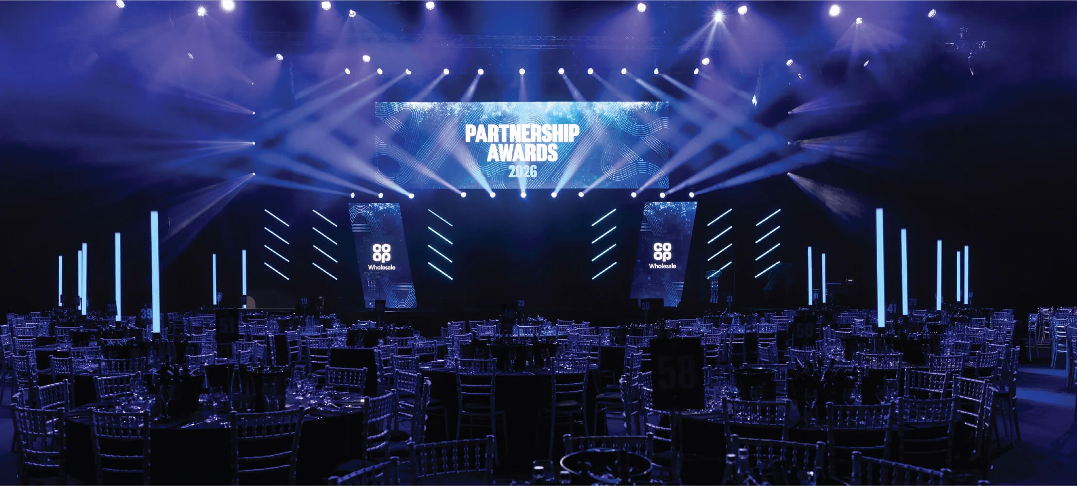 Conference stage with blue lighting and large screens