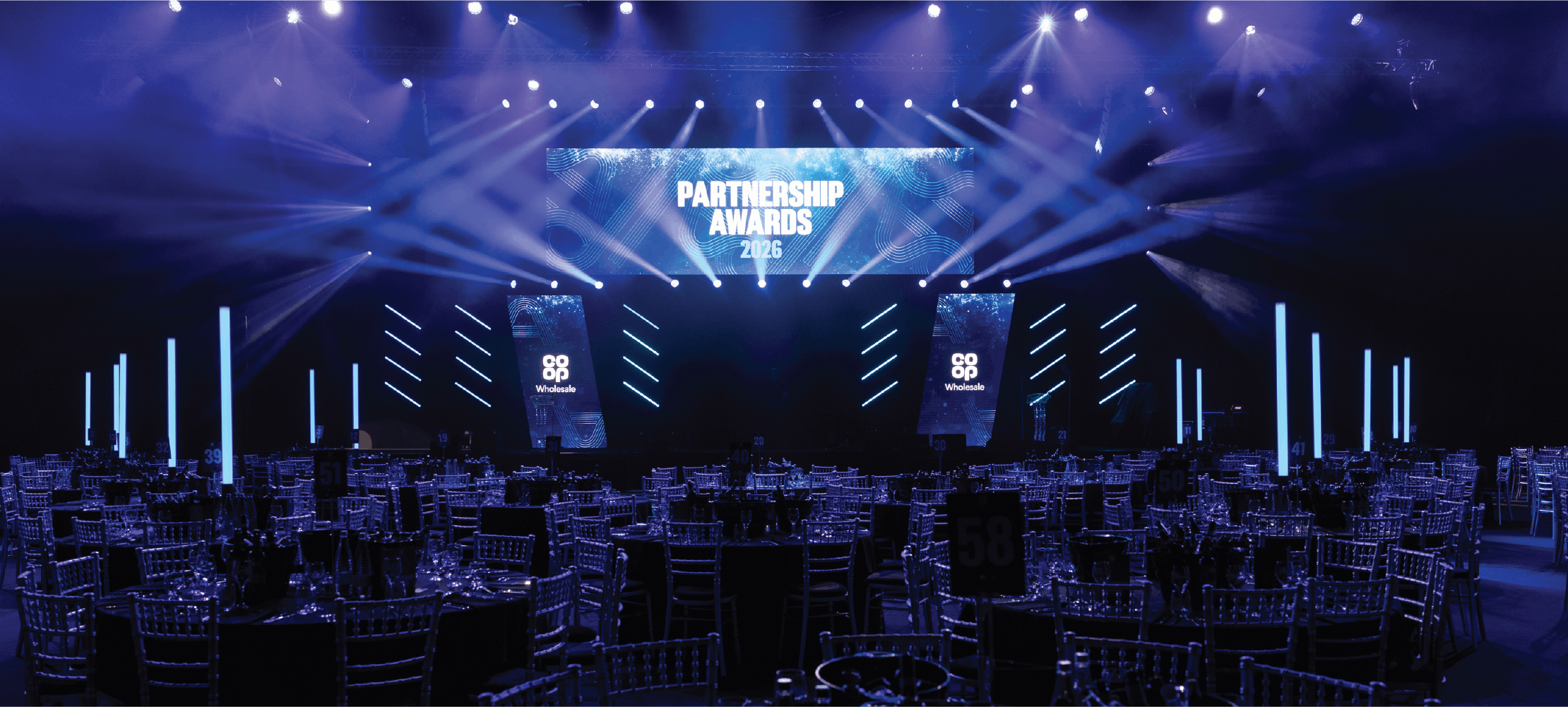 Conference stage with blue lighting and large screens