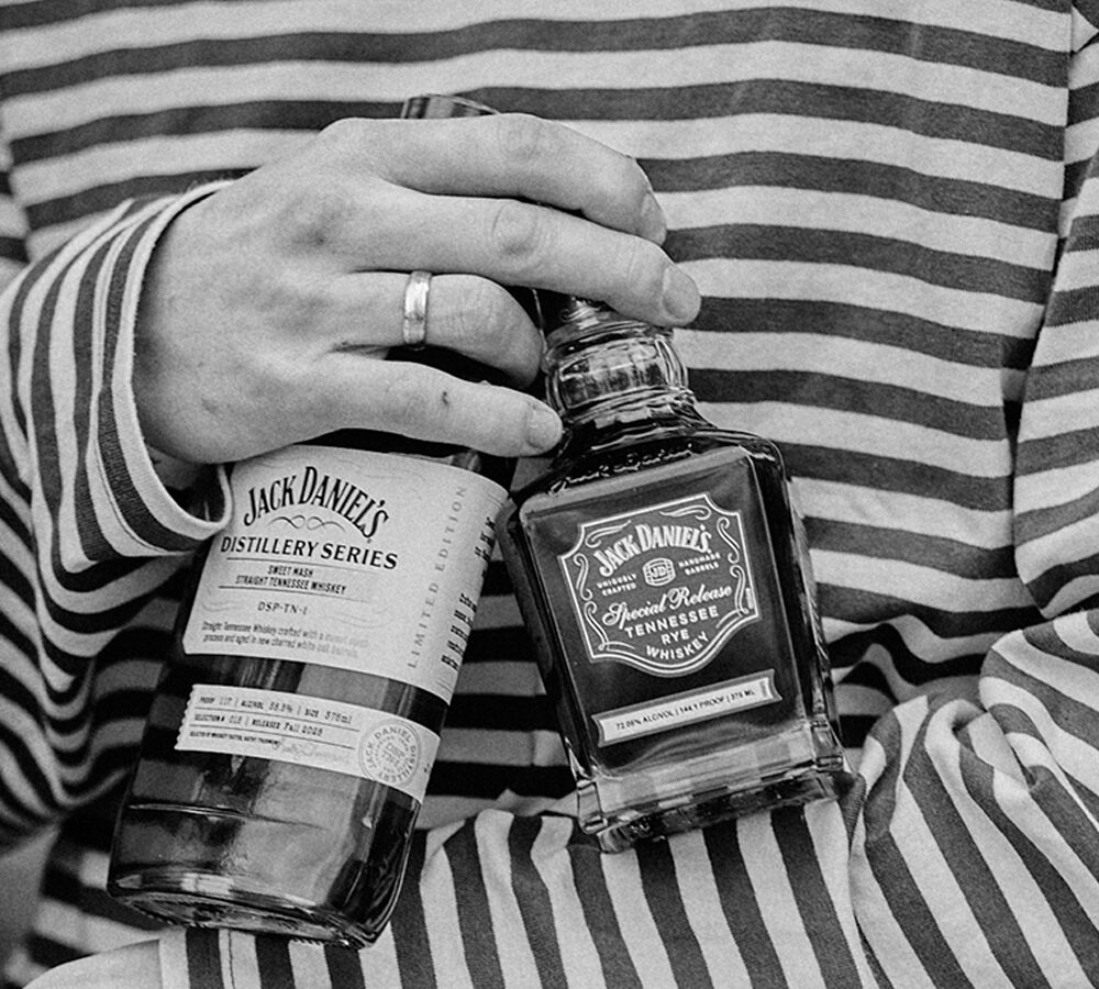 Black and white image of someone holding two Jack Daniel's bottles