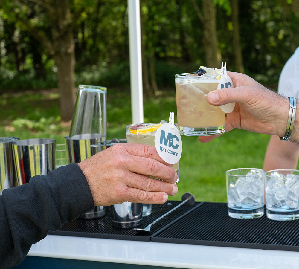 Golf day participants celebrating with drinks beneath a branded event gazebo.