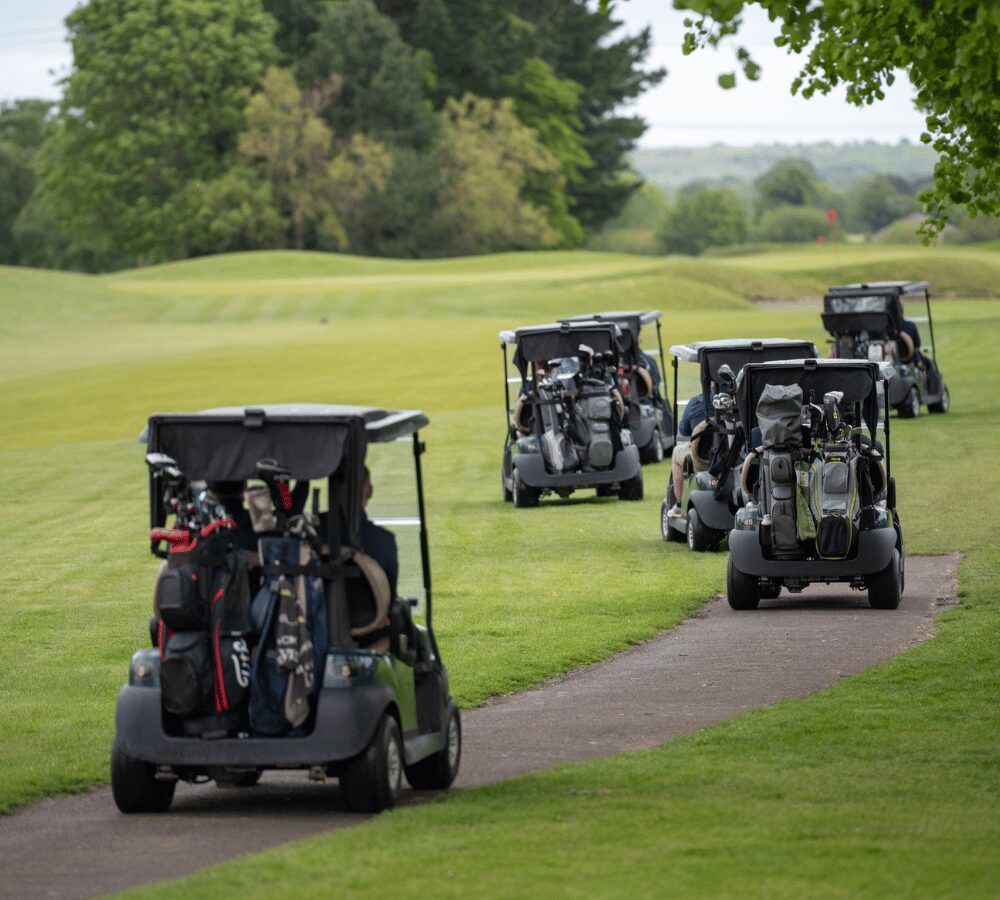 Golf buggies travelling across the course during a corporate golf day event.